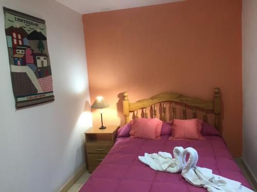 Una cama con sábanas rosas y toallas de cisne. en Apartamento Entre Olivos en Mendoza