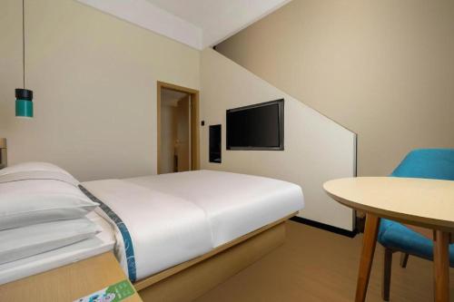 a bedroom with a bed and a table and a tv at City Comfort Inn Liuzhou Wuling Liutai Road in Liuzhou