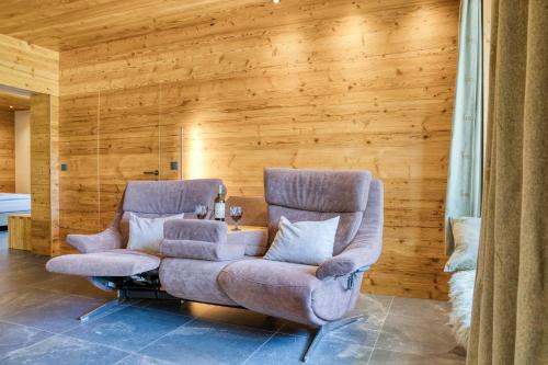 two chairs and a table in a room with wooden walls at Gästehaus Alpina in Krün