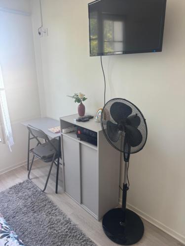 a room with a desk with a fan and a table at Studio lumineux avec WiFi gratuit Centre Antony, accès rapide Paris & Orly in Antony