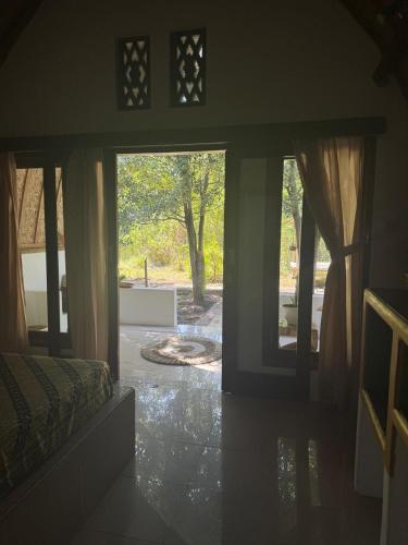 a room with a door open to a yard with trees at Rising Sun Bungalows in Gili Meno