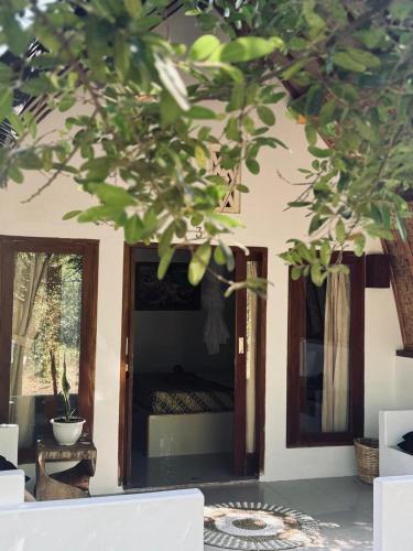 a room with a bed and a window and a tree at Rising Sun Bungalows in Gili Meno