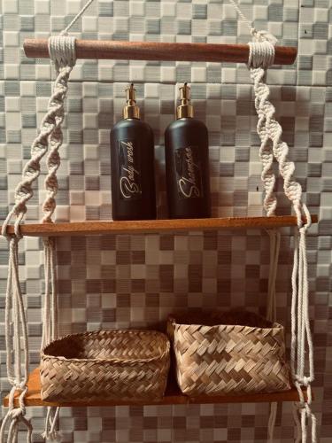 two black bottles on a shelf with baskets on it at Rising Sun Bungalows in Gili Meno