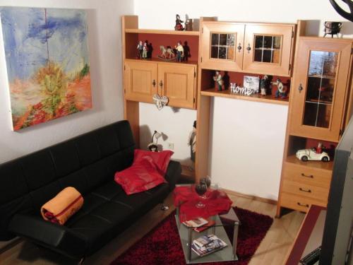 ein Wohnzimmer mit einem schwarzen Sofa und einem Tisch in der Unterkunft Ferienwohnung Anne in Sankt Ulrich am Pillersee