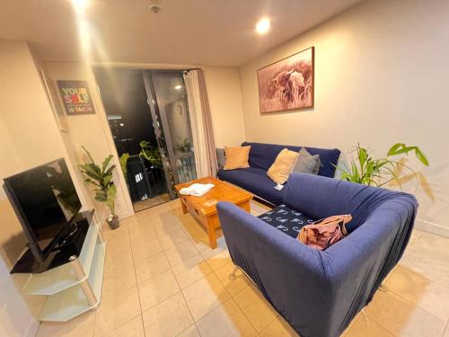 a living room with a blue couch and a tv at Authur's 2 bedrooms apartment, balcony, wifi, parking, cot, sunny, washing machine drier in Auckland