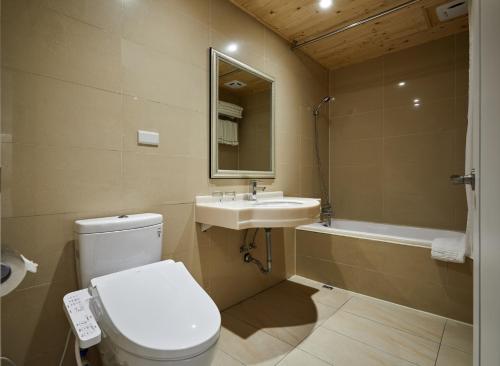 a bathroom with a toilet and a sink and a tub at K Hotel Keelung in Keelung