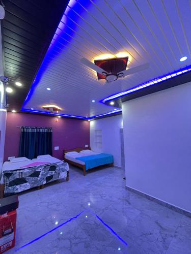 a room with two beds and a ceiling with purple lights at Dream lucky home stay hampi in Hampi