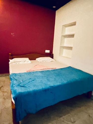 a small bed in a room with a red wall at Dream lucky home stay hampi in Hampi