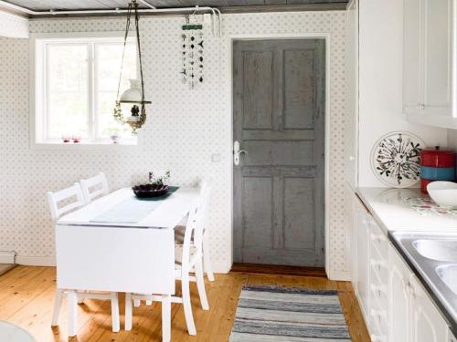 a kitchen with a white table and chairs and a door at 5 person holiday home in GAMLEBY in Karrum