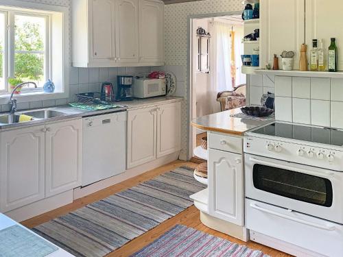 a kitchen with white cabinets and a stove top oven at 5 person holiday home in GAMLEBY in Karrum