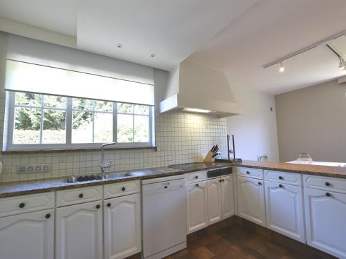 a kitchen with white cabinets and a window at Luxury Villa in Sint-Idesbald with Jacuzzi in Sint-Idesbald