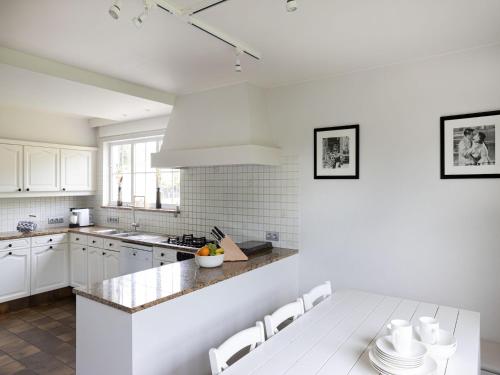 a kitchen with white cabinets and a table and chairs at Luxury Villa in Sint-Idesbald with Jacuzzi in Sint-Idesbald