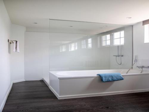 a white bathroom with a bath tub with a blue towel at Luxury Villa in Sint-Idesbald with Jacuzzi in Sint-Idesbald
