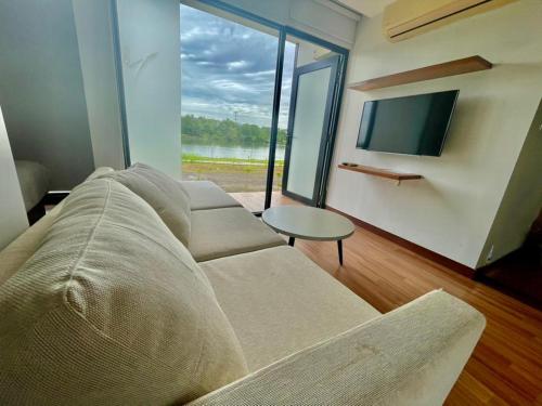 a living room with a couch and a tv and a table at Lakeview Terrace Resort Pengerang in Pengerang