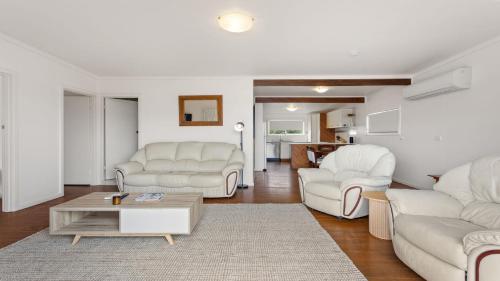a living room with white furniture and a table at White Springs, Our Peaceful Holiday House In Coffin Bay in Coffin Bay