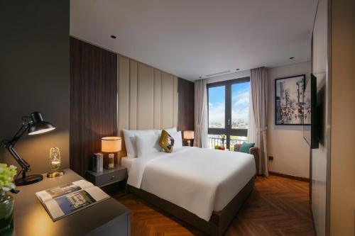 a hotel room with a bed and a desk and a window at Léman Old Quarter in Hanoi