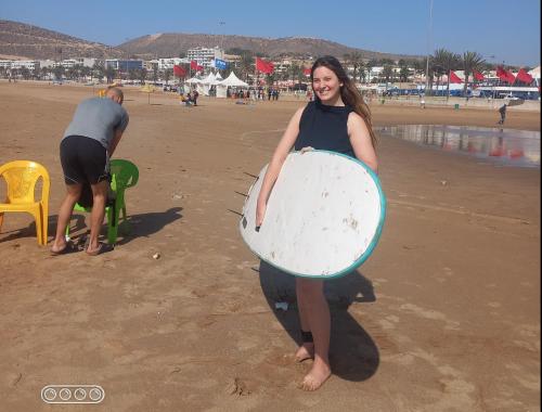 a woman standing on the beach holding a surfboard at Guest House Tamaris in Tamaris