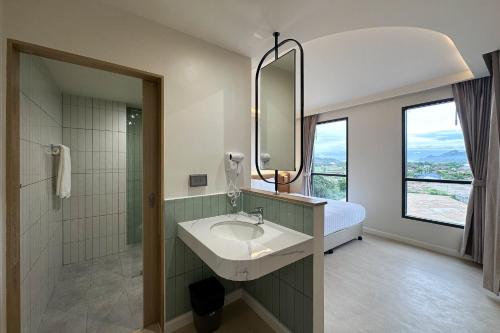 a bathroom with a sink and a bed and a mirror at G9 HOTEL Kanchanaburi in Ban Tukkata (1)
