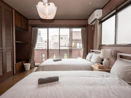 a bedroom with two beds and a large window at East Nagoya Entire 3-Story House in Nagoya