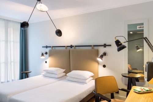 um quarto com uma cama com almofadas brancas e luzes em Hôtel Silky by HappyCulture em Lyon