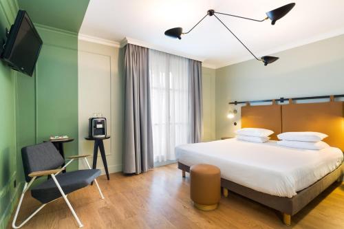 a hotel room with a bed and a chair at Hôtel Silky by HappyCulture in Lyon
