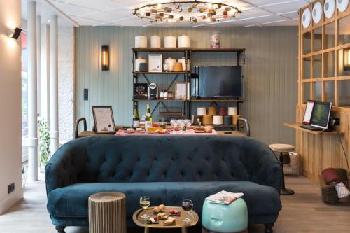a living room with a blue couch and tables at Hôtel Silky by HappyCulture in Lyon