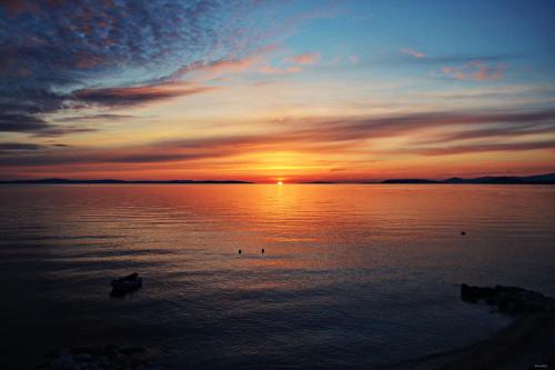 a sunset on a lake with a boat in the water at Apartment Hajdi in Podstrana