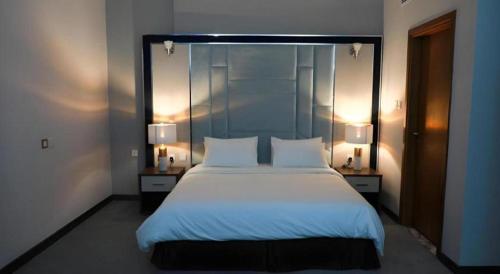 a bedroom with a large white bed with two lamps at ALAZMI HOTEL in Dubai
