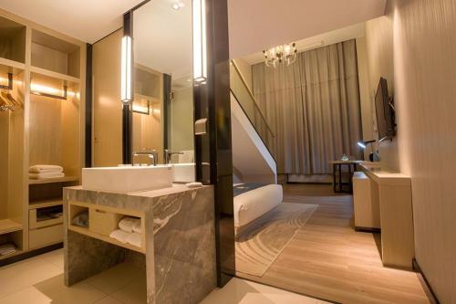 Un baño con lavabo y un espejo grande. en Echarm Hotel Wuhan Plaza Wansongyuan, en Wuhan