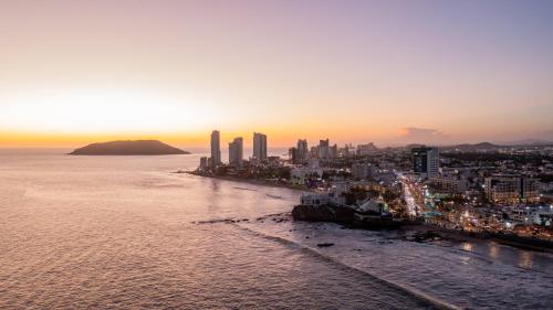a view of a city and the ocean at sunset at Holiday Inn Express & Suites Mazatlan by IHG in Mazatlán
