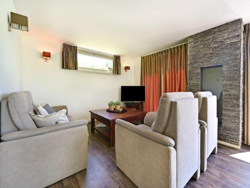 a living room with two chairs and a tv at Chalet in Reutum with Sauna and Nature in Weerselo