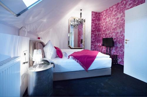 a bedroom with a bed with pink walls and a mirror at Ressmann`s Residence in Kirkel