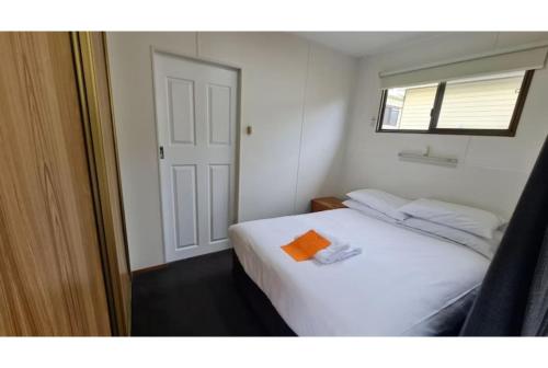 a bedroom with a white bed with an orange object on it at Discovery Parks - Mornington Hobart in Hobart
