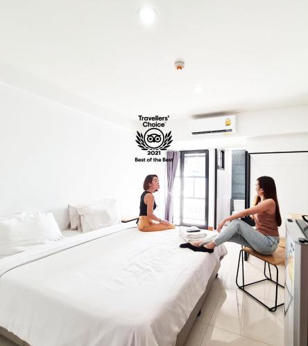 two women sitting on a large bed in a room at Don Muang Hotel in Bangkok