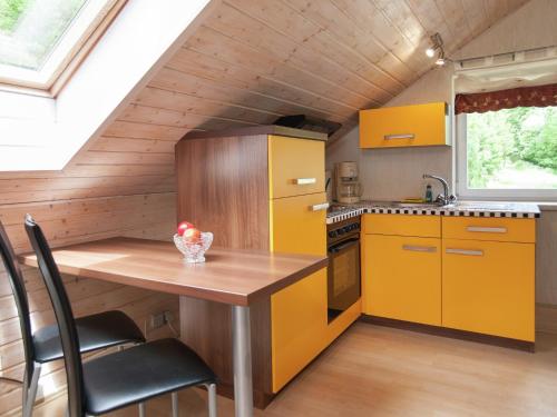 a kitchen with yellow cabinets and a wooden table at Apartment near Rennsteig in Goldisthal