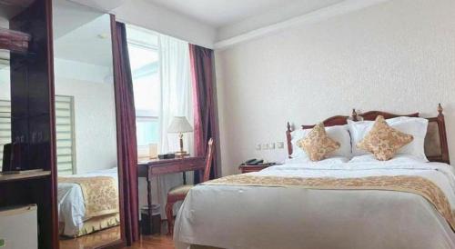 a bedroom with a large bed and a mirror at Yanji Yanbian International Hotel in Yanji