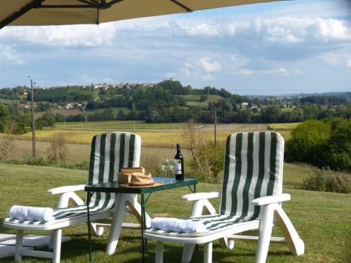 two chairs and a table with a bottle of wine at Labarthe in Baleyssagues