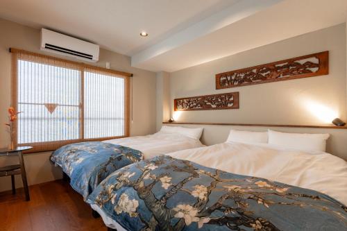 Un dormitorio con dos camas y un escritorio y una ventana. en 晴レ屋浅草 Hareya Asakusa, en Tokio