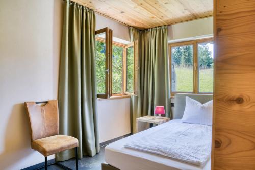 a bedroom with a bed and a chair and windows at Gästehaus Alpina in Krün