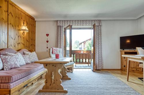 a living room with a couch and a tv at Gästehaus Alpina in Krün