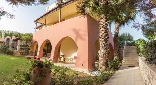 a pink house with a palm tree in front of it at Luxury Villa Karteros in Karteros