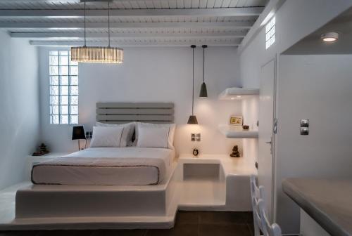 a white bedroom with a bed and a window at Aerides Mandrakia Milos in Mandrakia