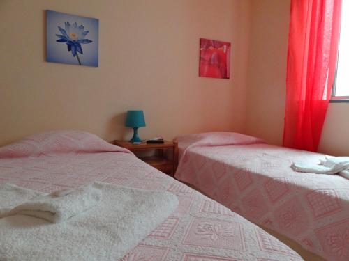 a bedroom with two beds and a window with red curtains at Residencial Espadinha in Quarteira