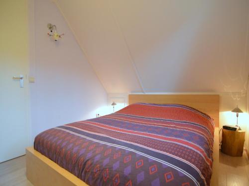 a bedroom with a bed with a striped blanket at Holiday Home in Heeten near Forest in Heeten