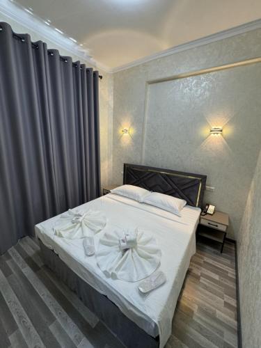 Un dormitorio con una cama con sábanas blancas y flores. en Diyor Tashkent Hotel, en Narimonow