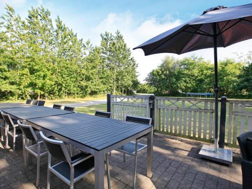 a wooden table with chairs and an umbrella at 12 person holiday home in Hojslev-By Traum in Bøstrup