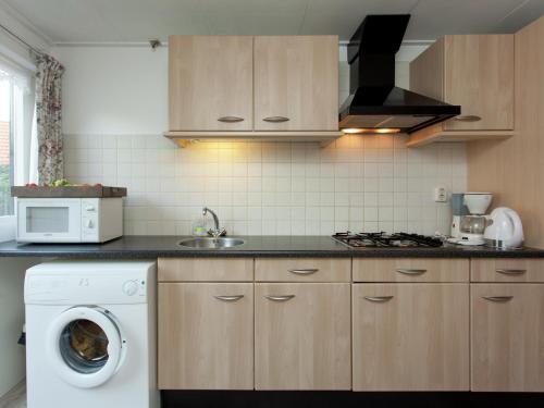 a kitchen with a washing machine and a microwave at Cottage in Nes-Ameland near Coastline in Nes