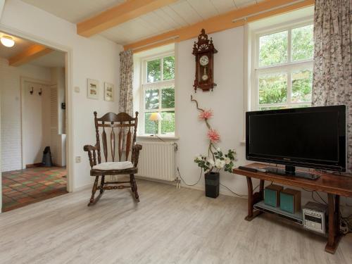 a living room with a flat screen tv and a chair at Cottage in Nes-Ameland near Coastline in Nes