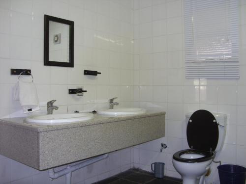 een witte badkamer met 2 wastafels en een toilet bij Ezulwini Berg Resort in Ethels Drive