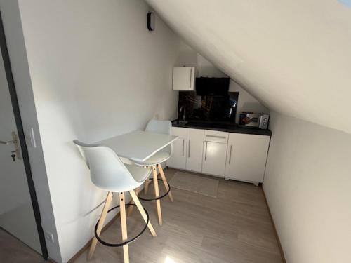 una mesa blanca y sillas en una habitación pequeña en Melo, en Plombières